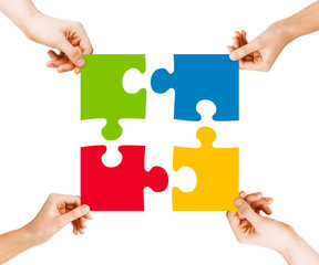 four hands connecting puzzle pieces