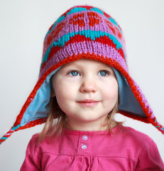 Cool stylish little girl with pink winter hat at light backgroun