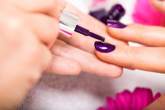 frau bekommt ihre n&auml;gel in lila lackiert nagelstudio manik&uuml;re