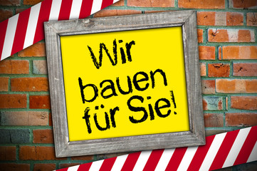 Schild mit Ziegelsteinmeuer und Wir bauen für Sie