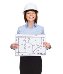 smiling businesswoman in helmet showing blueprint