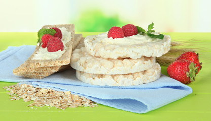 Tasty crispbread with berries, on green table