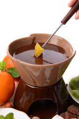 Chocolate fondue with sliced fruits, isolated on white