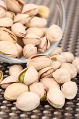 Pistachio nuts in glass bowl on table close up