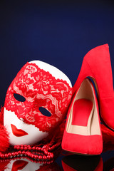 Beautiful red female shoes and carnival mask, on blue