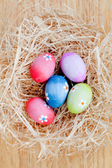Fototapeta na wymiar Easter eggs decorated with daisies on a nest of straw