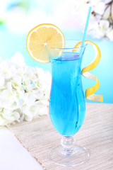 Glass of cocktail on table on light blue background