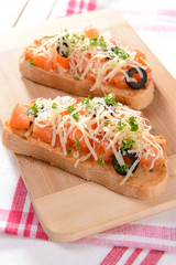 Delicious bruschetta with tomatoes on cutting board close-up