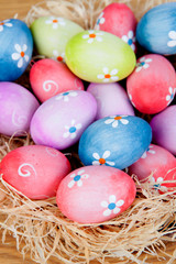 Easter eggs decorated with daisies on a nest of straw