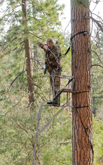 Bow hunter in a ladder style tree stand with bow at full draw, demonstrating good safety by using a...