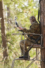 Bow hunter in a ladder style tree stand