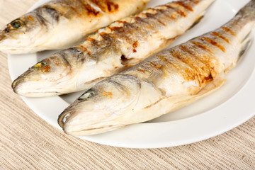 Delicious grilled fish on plate on table close-up
