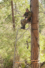 Bow hunter demonstrating good safety technique using a haul line to bring up his bow into a ladder style tree stand