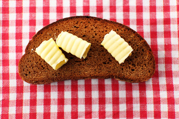 Slice of rye bread with butter, on tablecloth