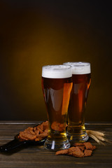 Glasses of beer with snack on table on dark background