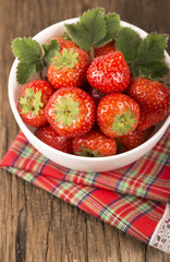 bowl with strawberries on wooden background
