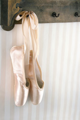 Ballet pointe shoes hanging from wooden rack