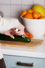 Caucasian attractive young woman is cutting cucumber.