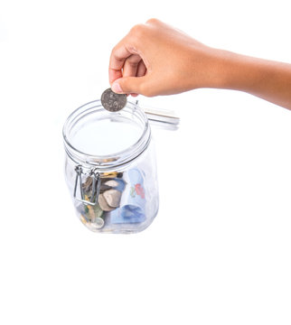A little girl hands putting coin in a money jar.
