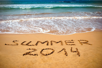 Inscription on wet sand Summer 2014. Concept of summer vacation.