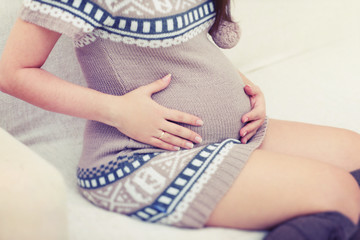Pregnancy, baby in a belly, pregnant young woman in a knit dress