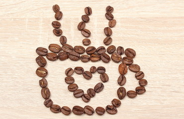 Cup of coffee beans with heart shape. Wooden background