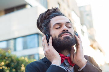 Stylish elegant dreadlocks businessman listening to music
