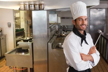Happy chef looking at camera with arms crossed holding ladle