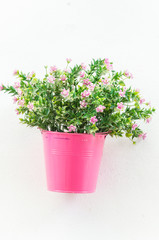 Plastic flower in vase on wall background