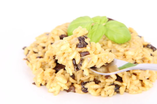 Risotto with mushrooms eaten with a fork on a white background