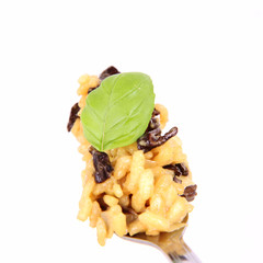 Risotto with mushrooms on a fork decorated with basil