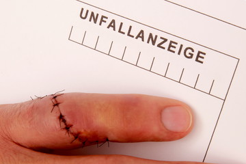 Mann mit genähtem Finger erstellt Unfallanzeige