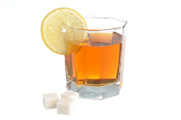Glass with a slice of lemon filled with lemon tea and refined su