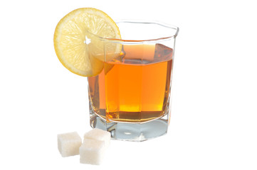 Glass with a slice of lemon filled with lemon tea and refined su