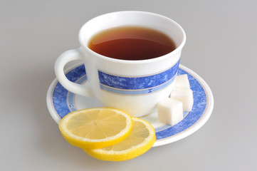 A cup of lemon tea and two slices of lemon, refined sugar on sau