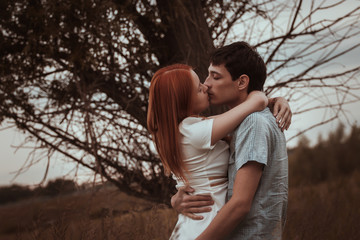outdoor portrait of young couple kissing in summer field