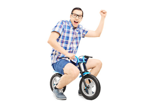 Young Man With Raised Fist Riding A Small Bike