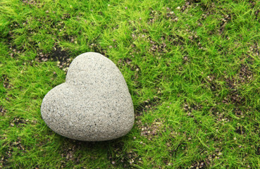 Grey stone in shape of heart, on grass background