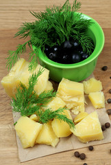 Parmesan cheese, fresh herbs and olives on wooden background