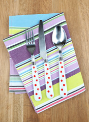 Kitchen cutlery on napkin on wooden table
