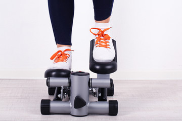 Woman doing exercise on stepper. Close-up on legs.