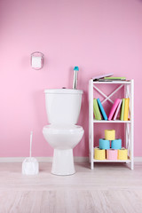 White toilet bowl and stand with books, on color wall