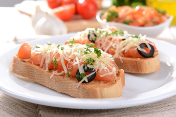 Delicious bruschetta with tomatoes on plate on table close-up