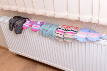 Knitted gloves drying on heating radiator