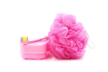 pink toothbrush, soapboxand shower scrubber on white background