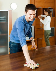 Man with wife dusting furniture