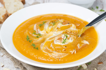 carrot soup with almonds, yogurt and watercress in a white plate