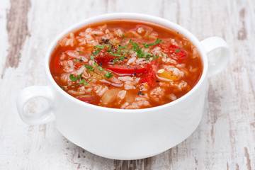 tomato soup with rice and vegetables on white wooden table