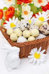 wicker basket with easter eggs, flowers and white rabbit