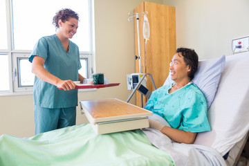 Friendly Nurse Bringing Breakfast For Patient In Hospital